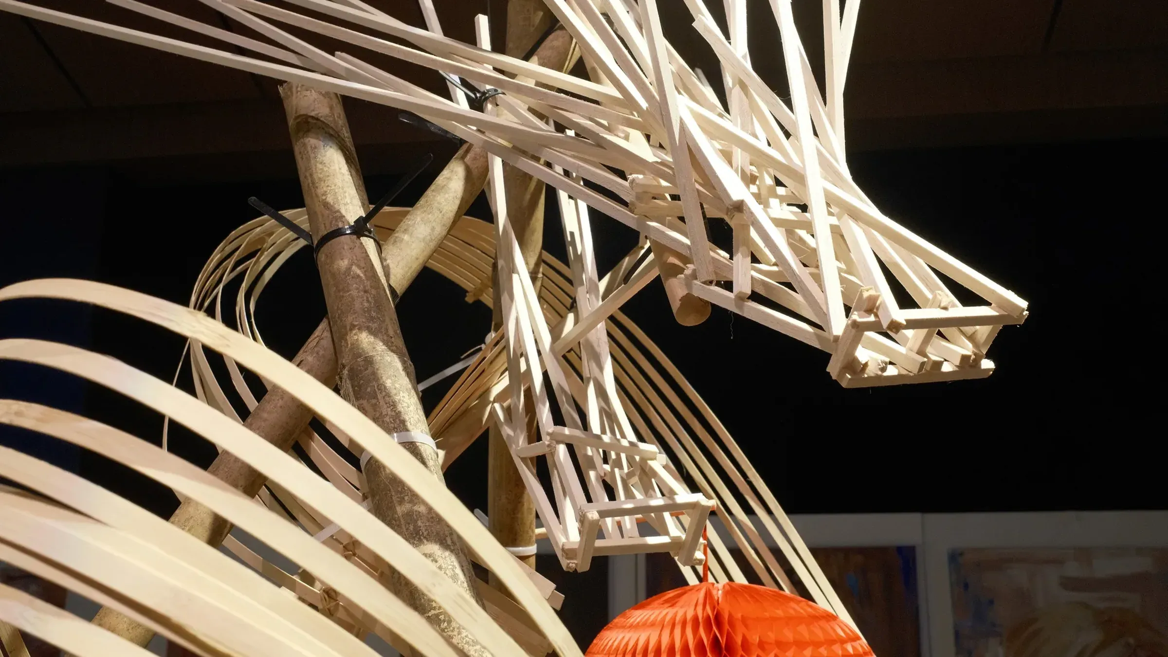The bamboo dragon's head in close-up, strips of bamboo over a red lantern